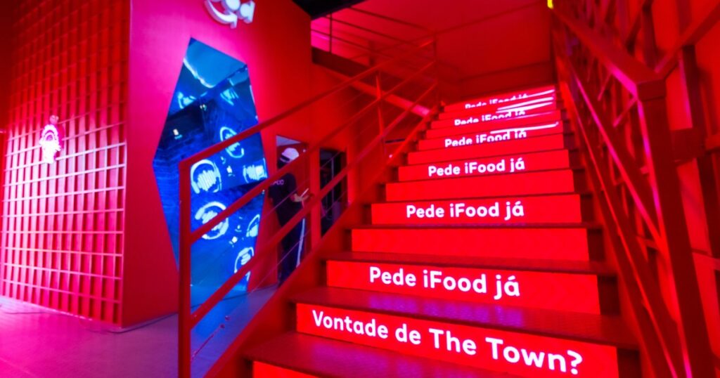 Imagem de uma ativação da iFood toda vermelha, a escada ao lado direito possui degraus em LED que mostram conteúdo dinãmico. 