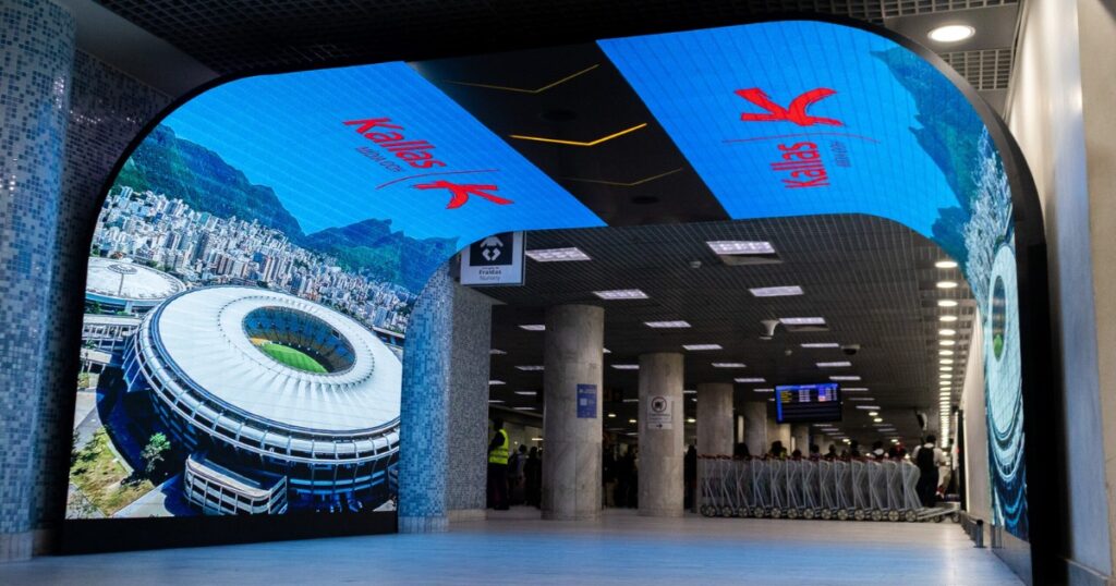 Imagem mostra o tunel de LED flexível instalado pela THE LED no aerporto Santos Dumont. O túnel exibe imagem do estádio do Maracanã e a palavra Kallas Mídia OOH, nome da empresa responsável pela administração do espaço publicitário.